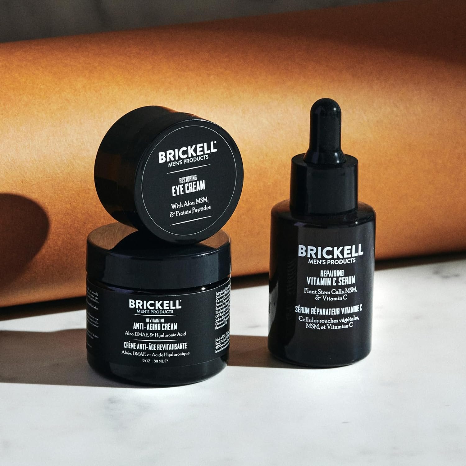 Vitamin C and peptide anti-aging skincare set for men including serum, night cream, and eye cream on minimal white background — view 2